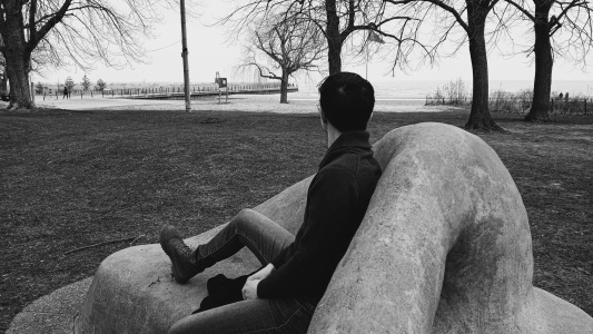 Alexia sitting on a sculpture at the lakeshore